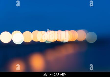 Line-up multi-colored lights blurred in abstact blue background image leadinig across horizon. Stock Photo