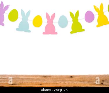 Wooden table and eggs and rabbits decoration garland on white wall. Easter holiday background Stock Photo