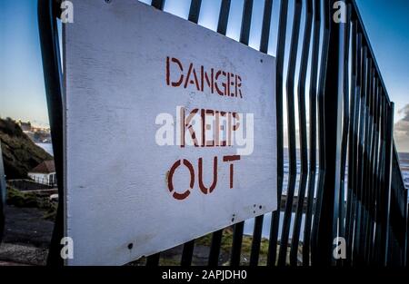 Danger Keep Out sign on metal fence near sea wall, Scarborough, Yorkshire, UK. Stock Photo