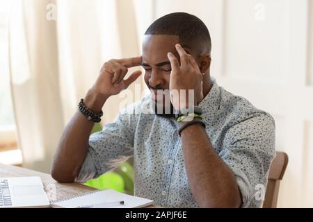 African overworked man suffers from migraine severe headache Stock Photo