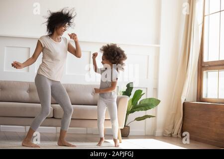 African daughter and mother dancing in modern living room Stock Photo