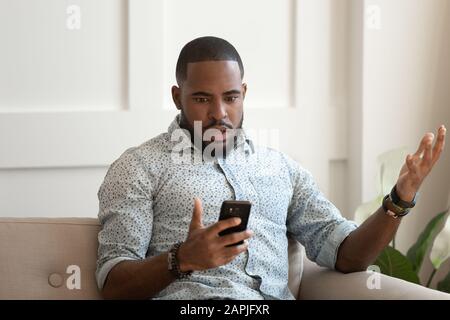 African man holds cellphone read sms feels shocked Stock Photo
