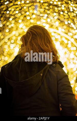 Girl seen from behind with christmas lights in the background Stock Photo