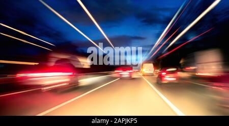 Driving fast on the highway or German Autobahn at night, cars and lights with motion blur Stock Photo