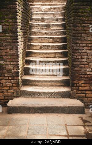 Ancient stone stairs with brick wall aside. Stock Photo