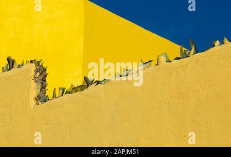 House wall with anti-climb broken glass against blue sky. Abstract architecture. Stock Photo