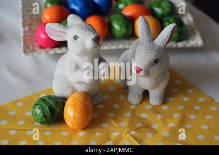 Colorful and joyful Easter decorations on a table. Closeup color image of two ceramic Easter bunnies and colorful painted Easter eggs. Stock Photo