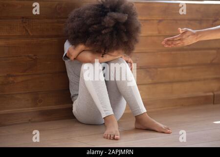 Woman holds out her hand to crying abandoned african child Stock Photo