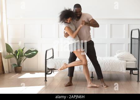 African couple in love holding hands dancing in morning indoors Stock Photo