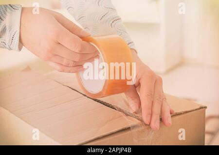 Hand holding the adhesive tape and taping the cardboard box Stock Photo
