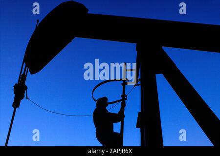 Oil and gas technician doing maintenance on a pumpjack Stock Photo