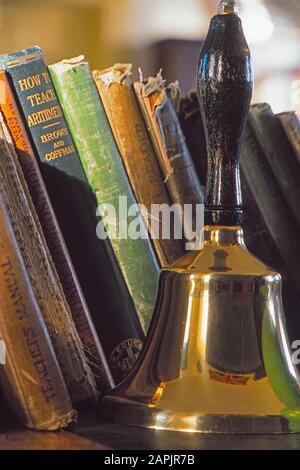 Vintage schoolhouse with books and a hand bell (handbell) Stock Photo