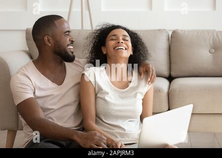 Cheerful african couple having fun using online websites at home Stock Photo