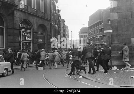 Riot police carry crowd-control barriers along a smoke-filled road in ...