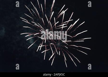 Cheap white fireworks against the dark sky. Stock Photo