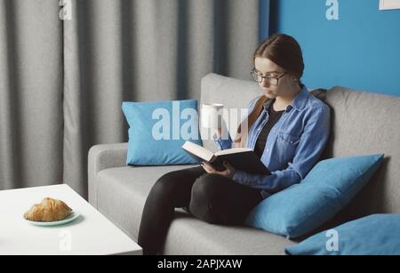 Girl reading resting on sofa Stock Photo