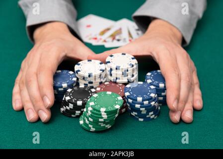 Man plays poker in the casino. Man collecting stack of poker chips, gambling concept. Stock Photo