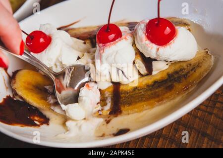 Banana split topped with cherries and bread pudding desserts sitting on a wooden table. Stock Photo