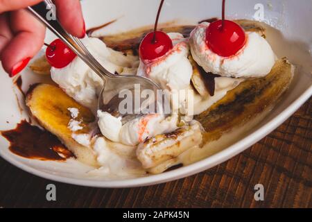 Banana split topped with cherries and bread pudding desserts sitting on a wooden table. Stock Photo