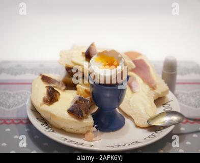boiled egg in a cradle with visible yolk on a plate with a croissant Stock Photo