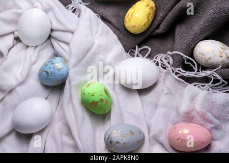 Easter eggs multicolored on the fabric. Easter background with eggs and feathers. Stock Photo