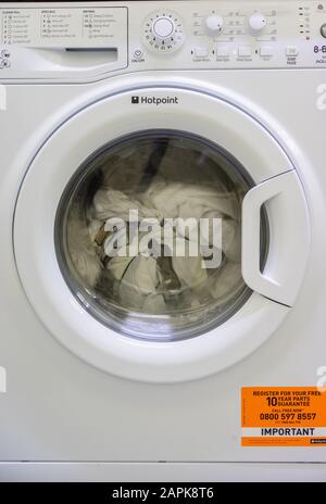 Hotpoint Aquarius washer dryer washing machine fully loaded with laundry inside a home in the UK Stock Photo