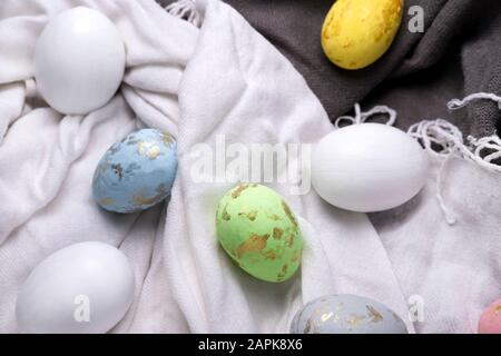 Easter eggs multicolored on the fabric. Easter background with eggs and feathers. Stock Photo