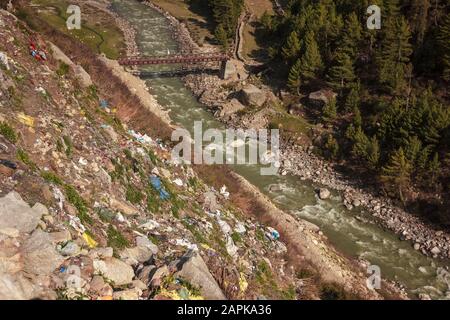 A steep hillside sloping down to the Baspa river littered with plastic trash thrown by tourists in the village of Chitkul in Himachal Pradesh, India. Stock Photo