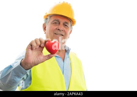 Old male engineer holding red rubber heart as love concept isolated on white studio background Stock Photo