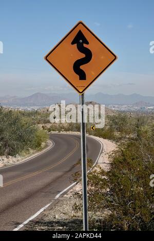 A street sign warning curves ahead for drivers driving through the Arizona desert. Stock Photo