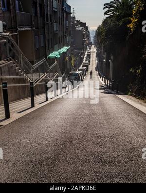 Early morning scene of an endless downhill street in the neighborhood of Gràcia, in Barcelona, Spain. Stock Photo