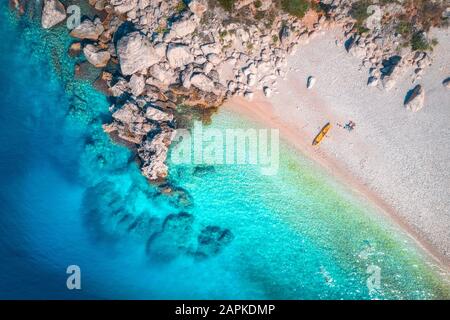 Aerial view of sandy beach with couple and canoe and blue sea Stock Photo