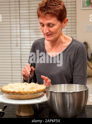 Woman cutting Thanksgiving dinner apple pie Stock Photo