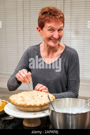 Woman cutting Thanksgiving dinner apple pie Stock Photo
