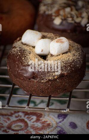 Chocolate glazed donut sprinklesd with cookie crumbs and mini marshmallows Stock Photo