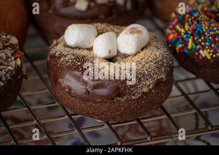 Chocolate glazed donut sprinklesd with cookie crumbs and mini marshmallows Stock Photo
