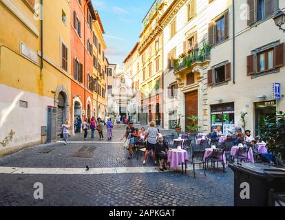 Local Italians including young people and an old woman enjoy a small piazza and cafe in the historic center of Rome, Italy. Stock Photo