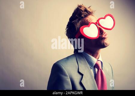 businessman wearing a pair of oversized heart shaped glasses puckering his lips for a kiss 2apkgwr