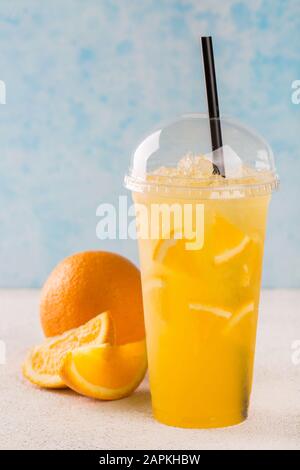 Orange lemonade in a plastic glass. Stock Photo