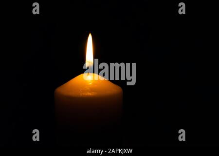 Single burning wax candle flame isolated on the black background Stock Photo