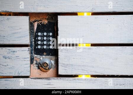 An old intercom with a magnetic key space mounted in the facade. There are wooden white boards around. Close up. Stock Photo