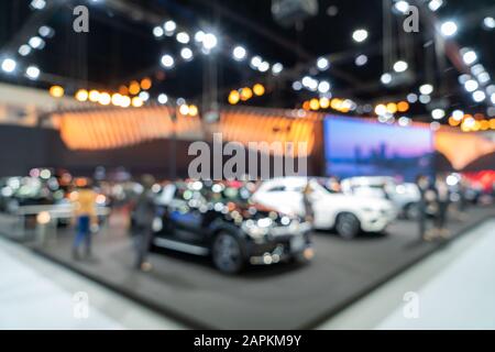 Blurred background of new cars displayed in luxury showroom with light bokeh, motor show event.
