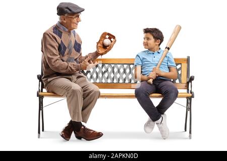 Elderly man with baseball glove and ball talking to a boy and sitting on a bench isolated on white background Stock Photo