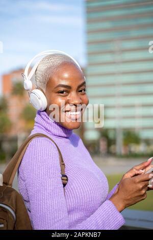 Portrait of white haired woman with white headphones listening to music in the city Stock Photo