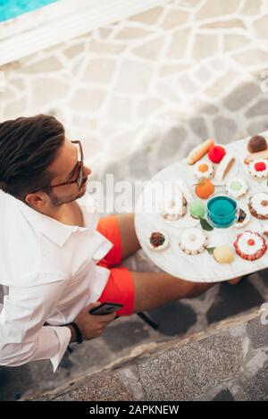 Handsome man sitting outdoors and drinking blue wine. Stock Photo