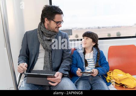 Father and daughter in metro and using tablet and smartphone Stock Photo