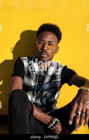 Portrait of young man with headphones against yellow wall Stock Photo