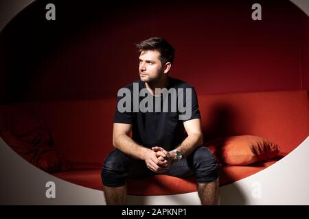 Young man sitting on couzch, thinking Stock Photo