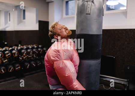 Man wearing pink bodybuilder costume practicing in gym Stock Photo