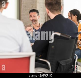 Business people having a meeting in office with one sitting in wheelchair Stock Photo